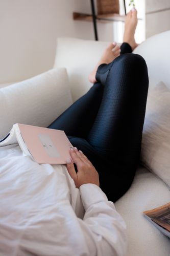 Frau trägt massierende FLOW leggings und liest dabei ein Buch