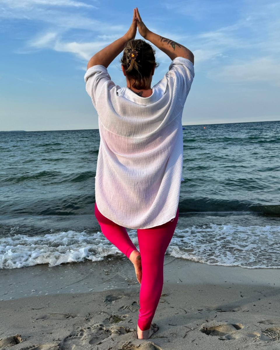 Lipödem Heldin Lyn macht Yoga am Strand und trägt dabei die pinke ACTIVE leggings von LIPOELASTIC